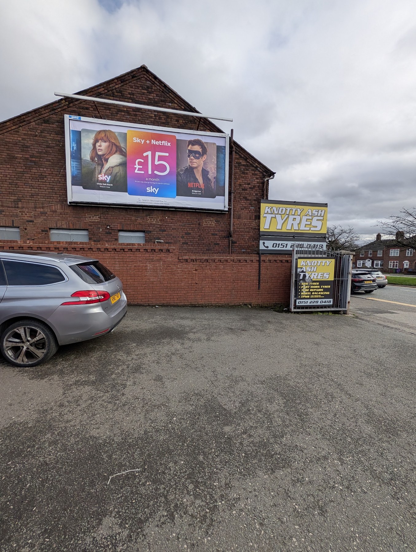 The entrance to the forecourt, with Knotty Ash Tyres signs on the gate and on the building