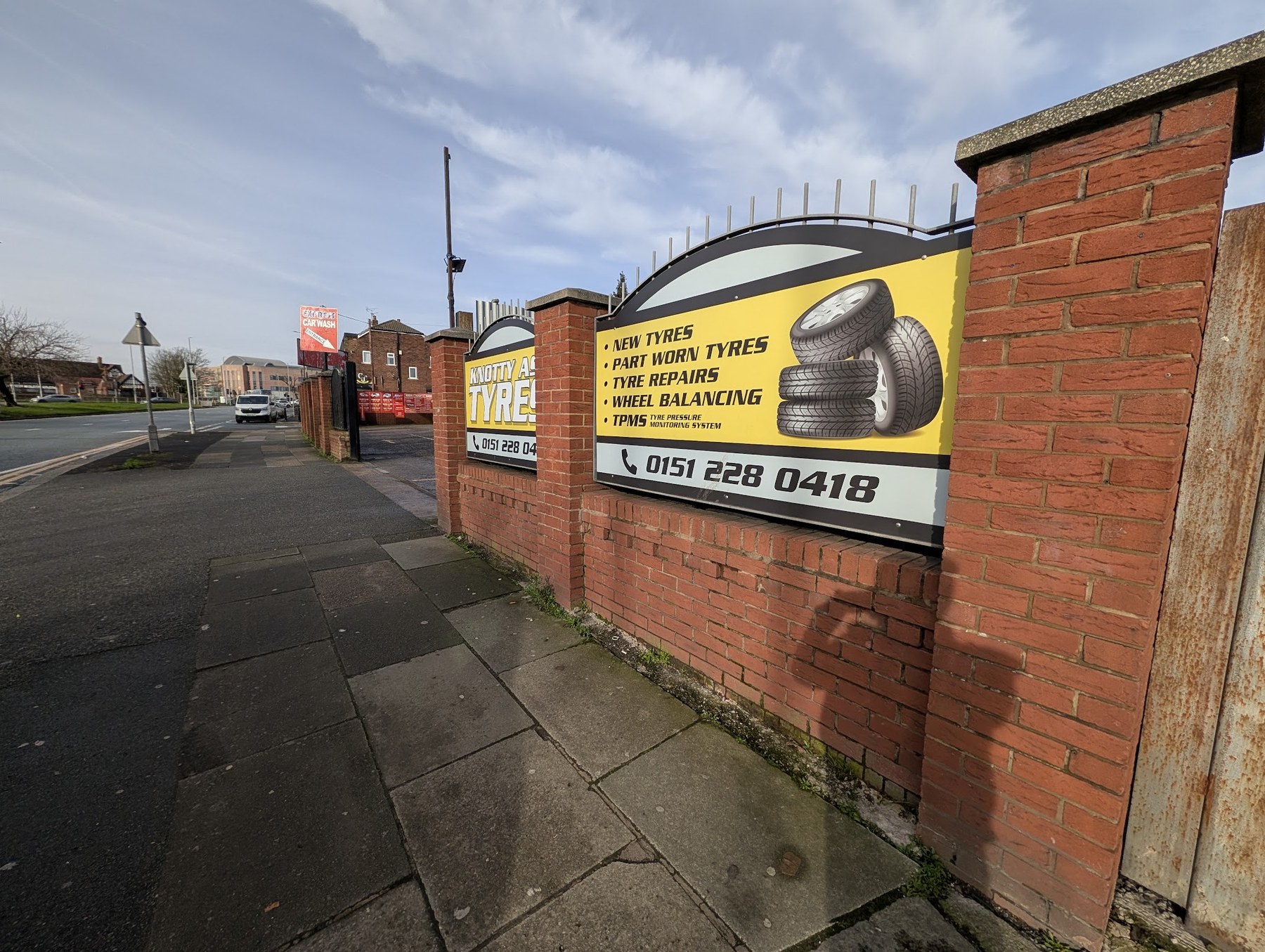 The yellow and black Knotty Ash Tyres signs on the brick wall along East Prescot Road